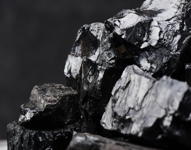 Natural coal on a black background isolated closeup. Extraction of natural mineral resources.